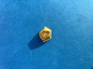 Small piece of solid gold on blue background