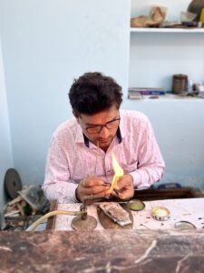 A goldsmith at his workbench in Jaipur, working over a flame